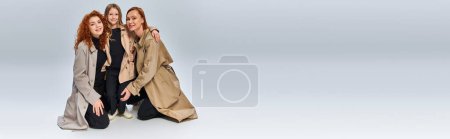Photo for Redhead family in coats and sitting together on grey background, happy female generations, banner - Royalty Free Image