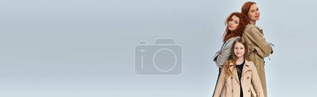 Téléchargez les photos : Fille rousse debout près de parents heureux en manteaux sur fond gris, génération féminine, bannière - en image libre de droit