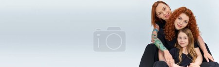Téléchargez les photos : Famille rousse en tenues assorties s'embrassant sur fond gris, trois générations, bannière - en image libre de droit