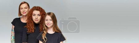 joyful women red hair posing with girl in matching outfits on grey backdrop, generations banner