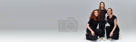 Téléchargez les photos : Portrait de famille, trois générations de femmes en vêtements assortis regardant la caméra sur gris, bannière - en image libre de droit