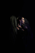 side view of woman in costume of fallen angel with dark wings praying in darkness, black backdrop Stickers #676127618