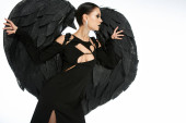 mysterious beauty, alluring woman in costume of black demon with wings posing on white backdrop Stickers #676128000