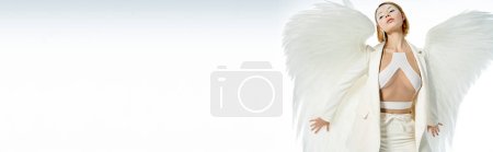 schöne Engelsfrau im Halloween-Kostüm mit himmlischen Flügeln posiert auf weißem Banner