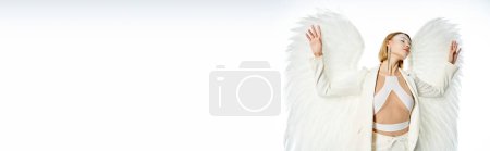 göttliche Schönheit, Frau im Kostüm eines hellen geflügelten Engels mit geschlossenen Augen auf weißem Hintergrund, Banner