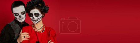 Elegantes Paar in Zuckerschädel-Make-up mit Blick in die Kamera auf rot, dia de los muertos festival, banner
