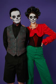 stylish couple in festive attire and dia de los muertos makeup looking at camera on blue backdrop Mouse Pad 676491328