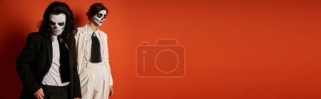 Téléchargez les photos : Couple élégant en die de los muertos crâne de sucre maquillage et tenue festive posant sur rouge, bannière - en image libre de droit