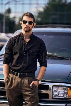 ansprechende elegante männliche Modell in schwarzen stilvollen Hemd mit den Händen in den Taschen Blick auf Kamera, Mode