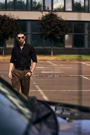 vertikale Aufnahme von verführerischen jungen männlichen Modell in stilvoller schwarzer Kleidung zu Fuß zu seinem Auto, sexy Fahrer