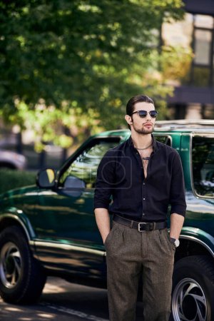 Foto de Tiro vertical de hombre encantador en traje negro elegante posando al lado del coche con las manos en los bolsillos - Imagen libre de derechos