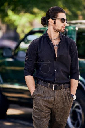 plan vertical de jeune homme sexy avec des accessoires avec les mains dans les poches posant devant sa voiture