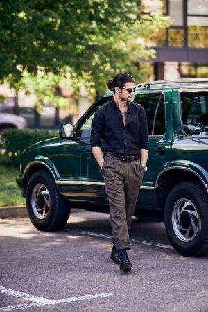 Photo for Handsome sexy man with sunglasses in black shirt walking near his car and looking away, fashion - Royalty Free Image