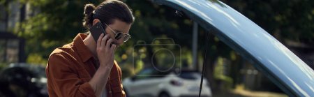 Téléchargez les photos : Beau jeune homme avec look dapper et lunettes de soleil parler à son assureur par téléphone, bannière - en image libre de droit