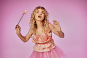 blonde curly haired woman with magic wand posing in pink tooth fairy costume on pink backdrop tote bag #676831580