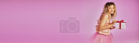 Photo for Beautiful blonde woman in tooth fairy costume holding present and looking joyfully at camera, banner - Royalty Free Image