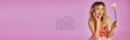 Téléchargez les photos : Femme joyeuse légèrement choquée en costume de fée dentaire tenant baguette magique sur fond rose, bannière - en image libre de droit