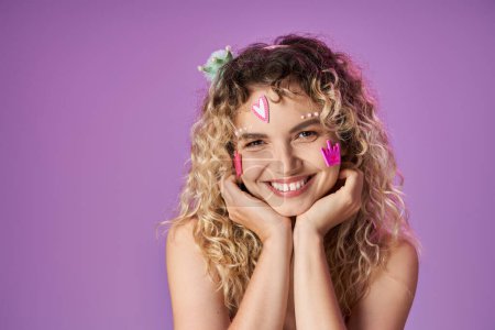 portrait of attractive woman in pink costume with face stickers looking cheerfully at camera