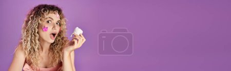 Photo for Amazed curly haired woman with face stickers holding tooth and looking shocked at camera, banner - Royalty Free Image