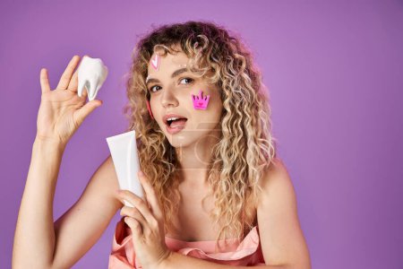 lovely attractive woman with curly hair and face stickers holding baby tooth and tooth paste