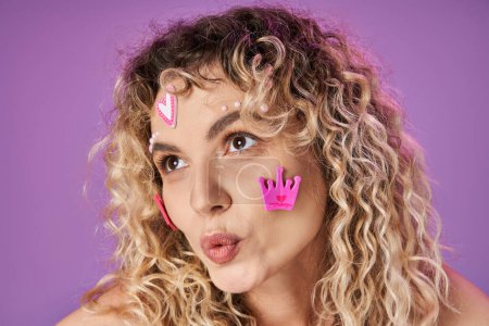 portrait of amazed attractive woman with blonde curly hair and bright face stickers looking away