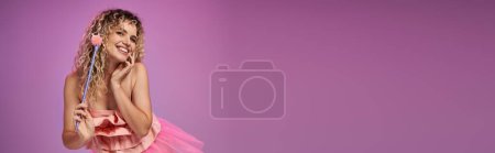 bonito hada de los dientes en traje rosa vibrante sosteniendo varita mágica y sonriendo a la cámara, pancarta