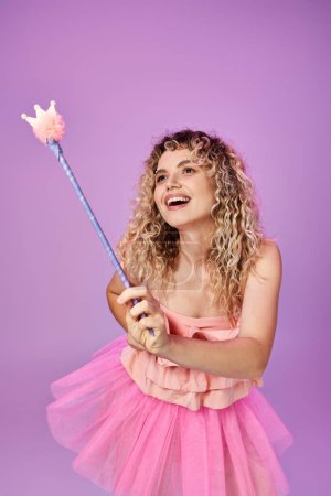 Foto de Hermosa mujer en vestido rosa hechizo de lanzamiento con varita mágica y mirando hacia otro lado, concepto de hada diente - Imagen libre de derechos