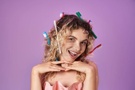 Photo for Lovely attractive tooth fairy with toothbrushes in her curly hair smiling cheerfully at camera - Royalty Free Image