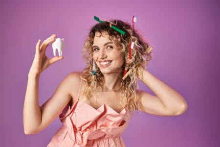 cheerful tooth fairy with toothbrushes in hair looking at baby tooth and touching her hair