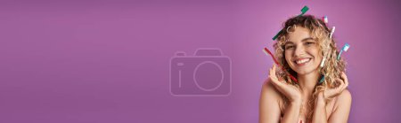 Téléchargez les photos : Femme blonde joyeuse en tenue rose festive avec des brosses à dents dans ses cheveux posant sur la caméra, bannière - en image libre de droit