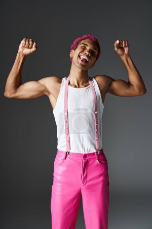 hombre juguetón y elegante con el pelo rosa mostrando los músculos y sobresaliendo lengua, moda y estilo