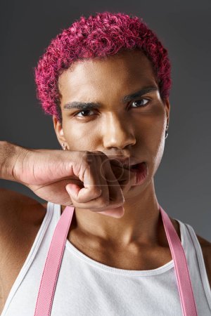 Porträt eines ernstzunehmenden, rosafarbenen Mannes mit der Faust im Gesicht, der in Kamera, Mode und Stil blickt