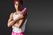 fashionable handsome male model with pink hair posing with toy gun looking seriously at camera t-shirt #677104130