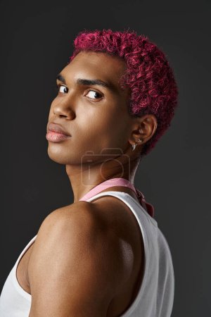 Téléchargez les photos : Portrait de beau jeune homme aux cheveux roses regardant la caméra sur fond gris, concept de mode - en image libre de droit