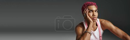 Téléchargez les photos : Élégant homme afro-américain en tenue vibrante avec la main sur le visage en regardant la caméra, la mode, la bannière - en image libre de droit