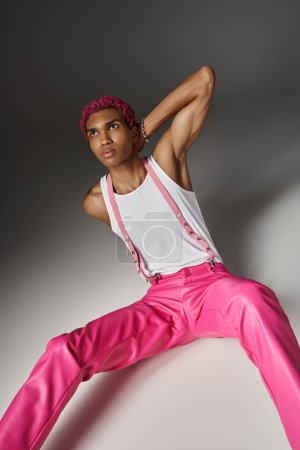 Photo for Good looking male model with pink hair sitting on floor with hand behind neck, fashion concept - Royalty Free Image