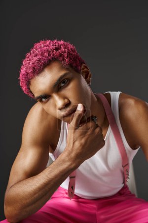 portrait of good looking pink haired man in stylish attire with hand on his lips, fashion concept