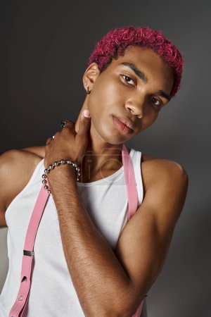 portrait of pink haired man in voguish vibrant outfit with hand on his neck, fashion concept