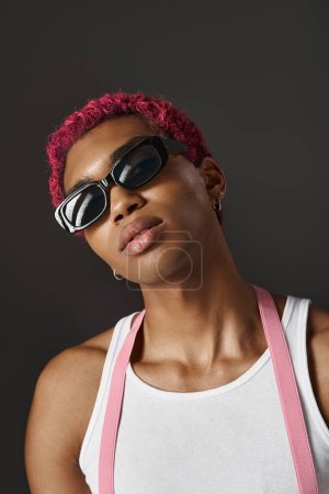 Porträt eines stilvollen männlichen Modells mit rosa Haaren, das Sonnenbrille vor der Kamera trägt, Modekonzept