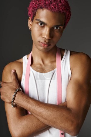Porträt eines jungen, stylischen Mannes mit rosa Haaren, der mit leicht verschränkten Armen posiert, Modekonzept