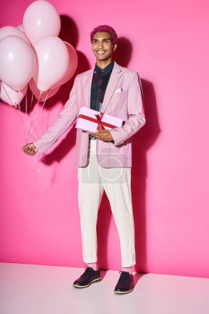 handsome african american male model posing unnaturally with balloons and present in hands