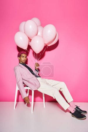 Photo for Handsome african american man looking straight at camera and holding balloons in hand, doll like - Royalty Free Image