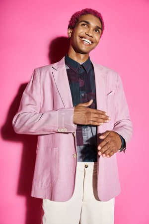 handsome young man acting unnaturally like doll smiling and posing on pink backdrop