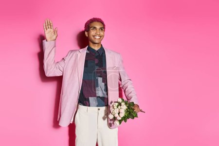 hombre afroamericano bien parecido sonriendo y actuando como muñeca masculina agitando y sosteniendo ramo de rosas