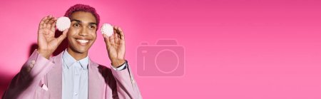 Téléchargez les photos : Homme joyeux avec délicieux zéfir rose près du visage sur fond rose, agissant comme une poupée masculine, bannière - en image libre de droit