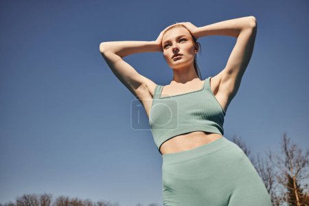Photo for Blonde and sporty woman in cycling shorts and crop top standing and looking away after workout - Royalty Free Image
