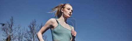 Foto de Mujer deportiva rubia y en forma en ropa deportiva corriendo al aire libre, la motivación y el banner deportivo - Imagen libre de derechos