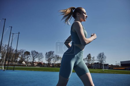 Téléchargez les photos : Vue latérale de blonde fit femme en short de cyclisme et crop top courir à l'extérieur, la motivation et le sport - en image libre de droit