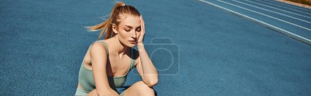 young tired sportswoman in activewear sitting while having rest after workout, horizontal banner