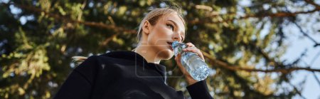 banner of young woman with blonde hair and sportswear drinking water after working out in park